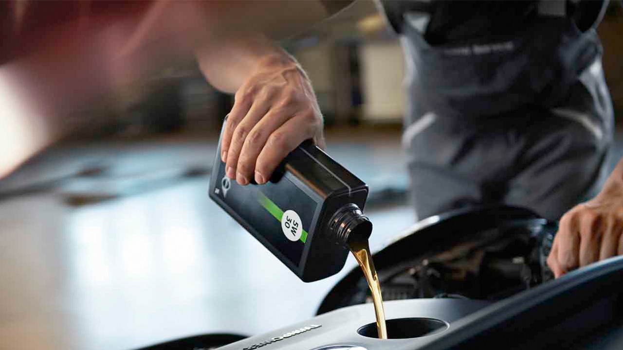 Technicien versant de l’huile moteur dans le compartiment moteur d’une MINI.